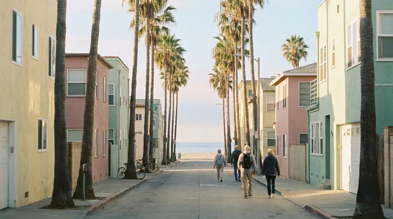 A quiet Venice, California street at dawn with palm trees and the beach at the end